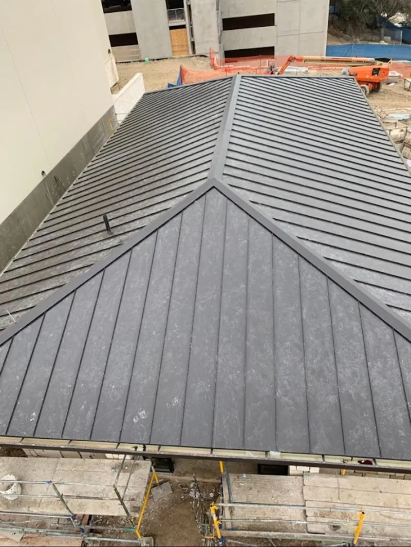 Commercial metal roof construction with crane equipment in Stoneham